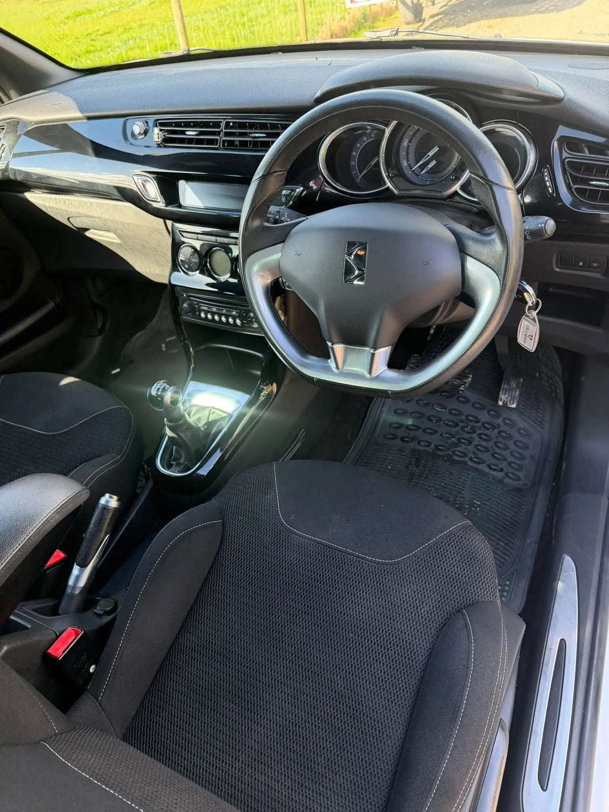 A clean, front-facing view of a car's interior, showing the black fabric seats, steering wheel, dashboard, and gear shift console. The DøSER logo is visible on the steering wheel center.